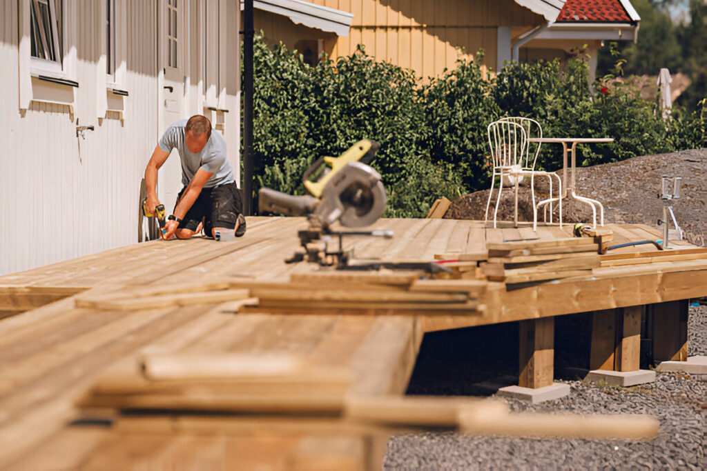A contractor installing wooden planks for a new outdoor patio deck
