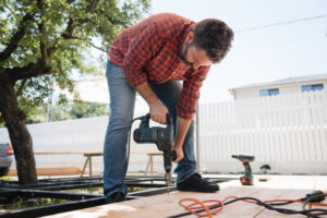 Professional contractor working on a deck with power tools outdoors