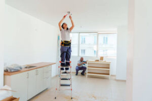 Worker installing ceiling fixtures during whole house renovation